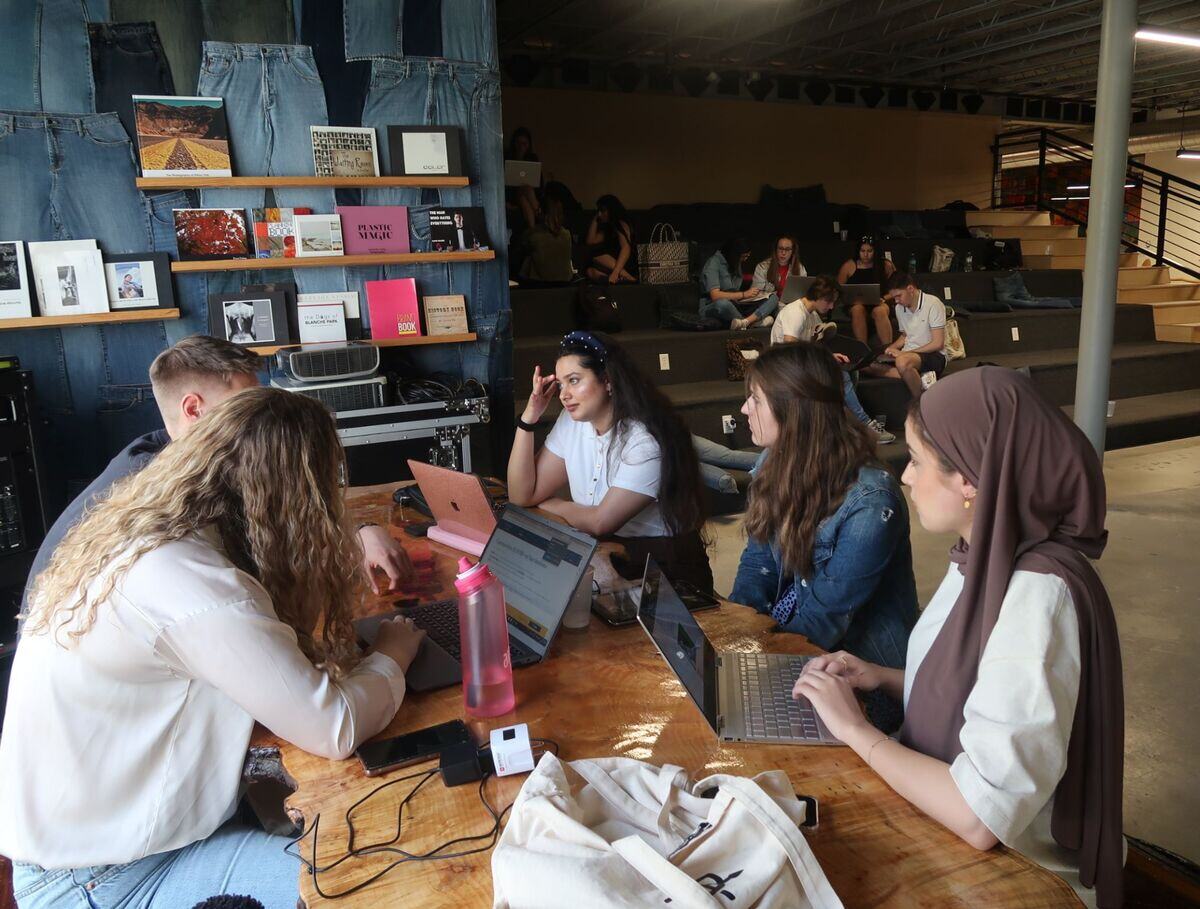 A group of people sitting at a table with laptops, collaborating on a project.